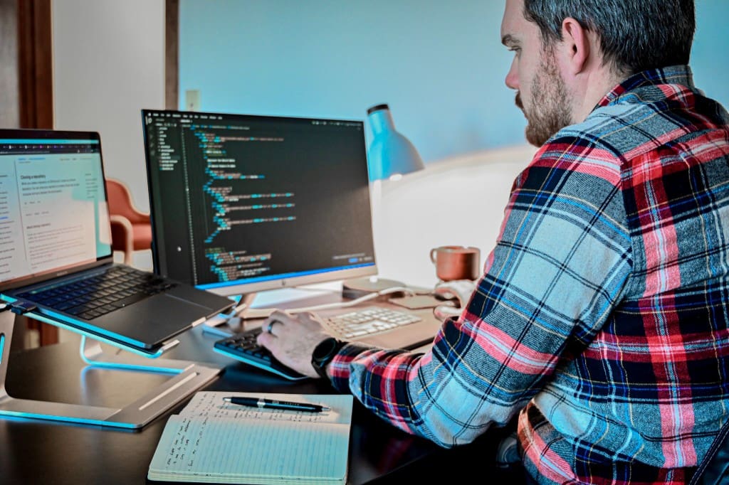 Ben Noble working at a desk with code on screen managing WordPress hosting and site updates